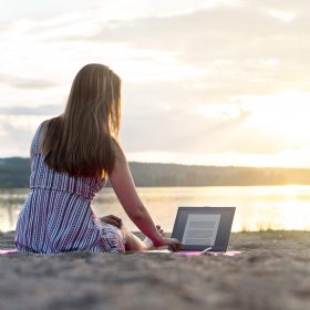 Work-life balance symbolized by a young lady relaxing on the beach with her laptop
